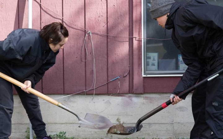 two students shovel dirt during a service project with outward bound